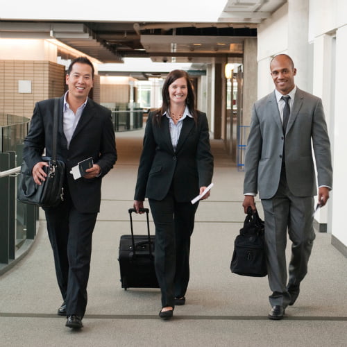 Imagem de três profissionais com malas de viagem fazendo turismo corporativo, uma atividade que precisa de um serviço de câmbio.