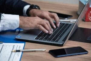 Imagem mostra um homem utilizando o notebook para executar alguma ação, como preencher corretamente o ACAM220 nas operações de eFX.