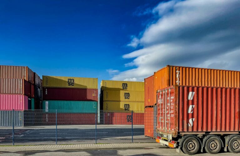 Esta imagem mostra contêineres em um porto com produtos que passam por processos de exportação, ilustrando o ranking dos produtos que o Brasil mais exporta. O ranking foi elaborado pela B2Gether, empresa de câmbio especializada em operações financeiras de exportação.