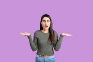 Na imagem, há uma mulher apresentando um semblante de dúvida. A imagem ilustra uma dúvida muito comum entre decisores financeiros: qual é a melhor opção para pagar uma importação: um banco, uma corretora ou um correspondente cambial?