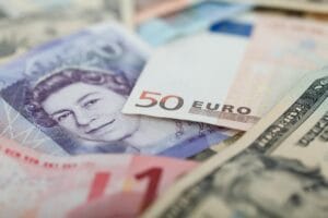 Na imagem, há notas de diferentes modeas estrangeiras, como euro e dólar americano, ilustrando como fazer uma operação de câmbio com segurança e economia.